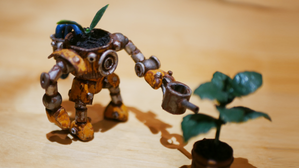 On a wooden table, a small rusty robot figure watering a plastic plant with a watering can.