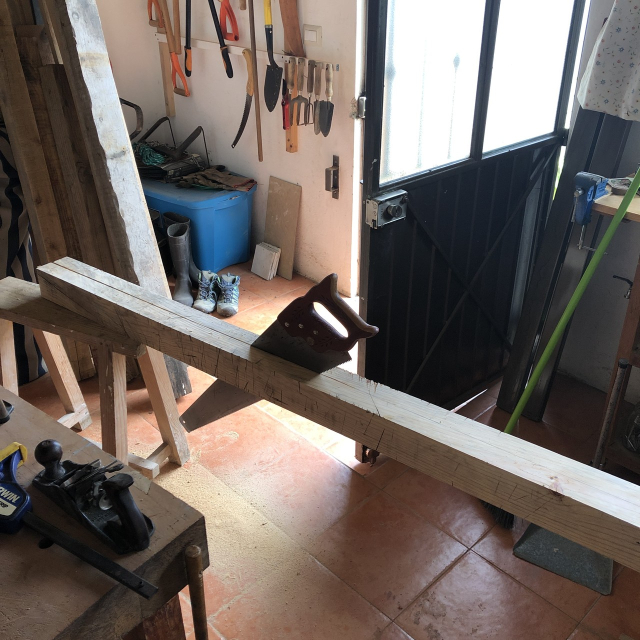 Serruchando una viga de 10x10 longitudinalmente. La viga está puesta sobre burritos de madera.