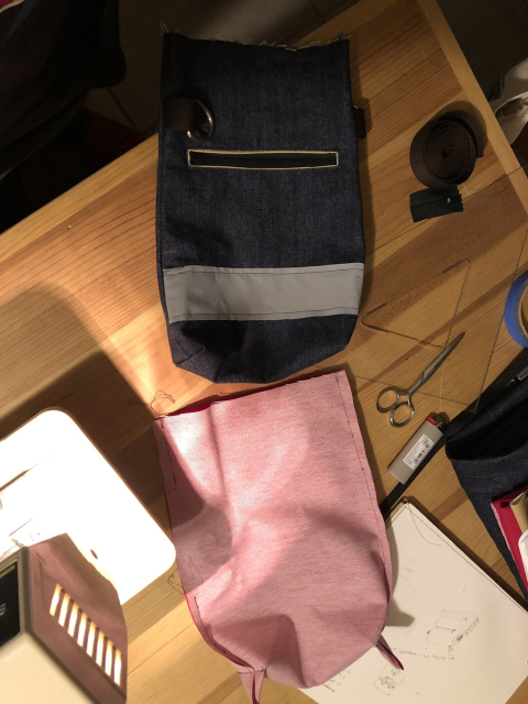 Outer bag in dark blue denim with reflecting tape and zippered pocket; inner bag in pink.