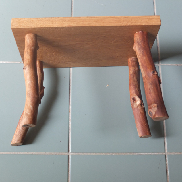 A view from below the stool. You can see the knots and twists of the peeled branches.