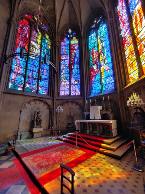 a chapel flooded by coloured light from modern semi-abstract glass windows in red, blue and yellow
