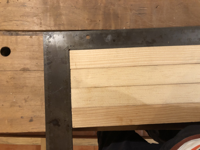 Cuatro tiritas de madera, que serán las columnas sobre las que va la trama. Las alíneo del extremo al mismo tiempo con una escuadra grande.