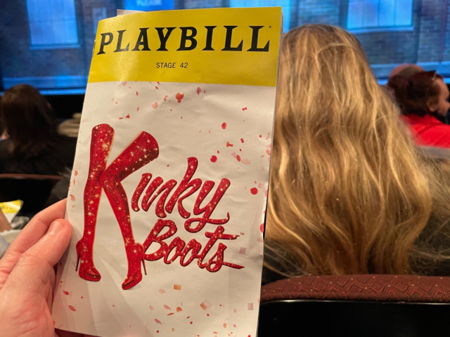 Photo of the Kinky Boots Playbill with the words “Kinky Boots” and a pair of thigh-high boots rendered in sparkling fire-engine red.