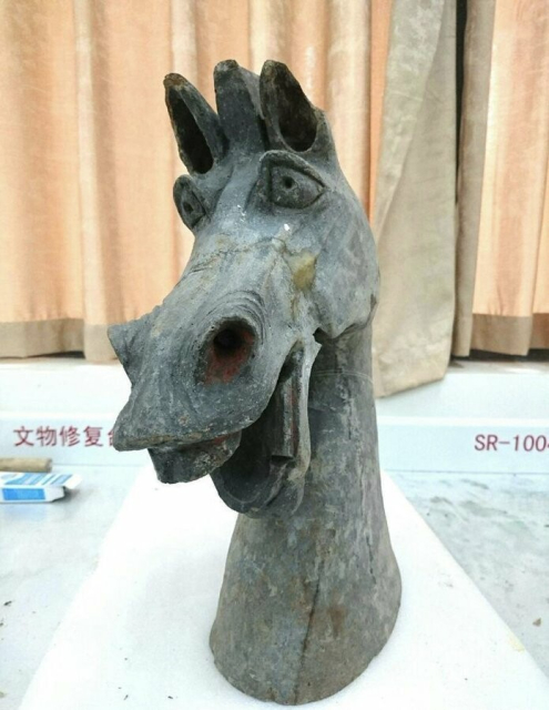 a very goofy Donkey-from-Shrek-looking ceramic statue from the Han Dynasty. it's got big cartoon eyes and its mouth is open in a big cartoon horse grin and its head is tilted slightly to the side, it looks really fun 