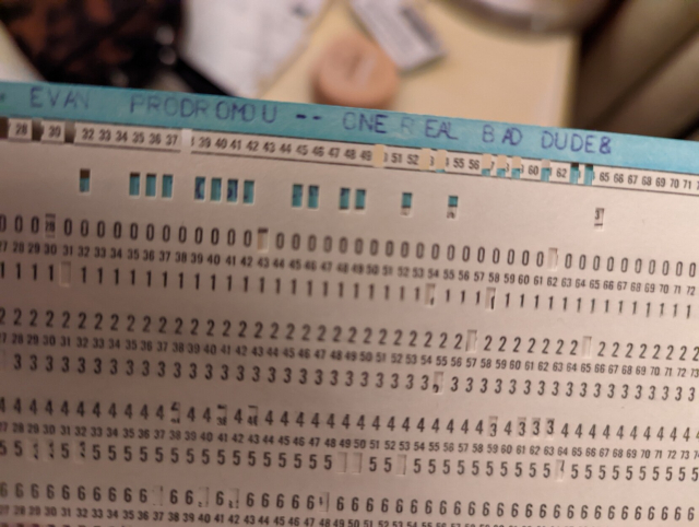 An antique computer punch card with "EVAN PRODROMOU ONE REAL BAD DUDE" typed on it