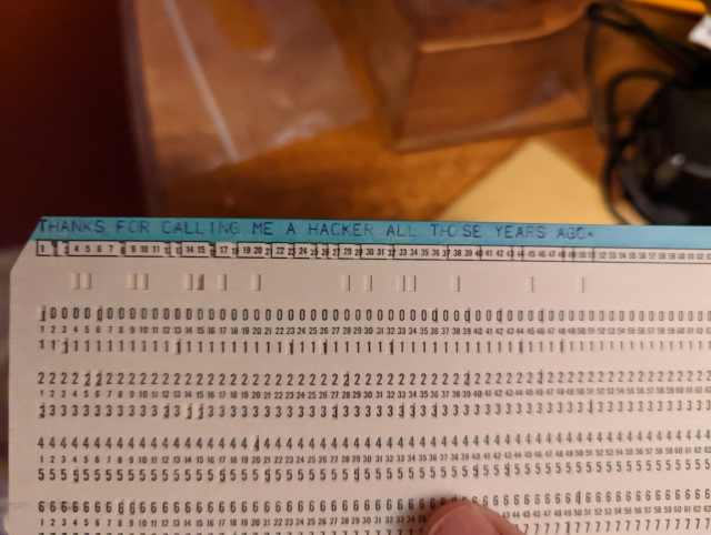 An antique computer punch card with "THANKS FOR CALLING ME A HACKER ALL THOSE YEARS AGO" typed on it.