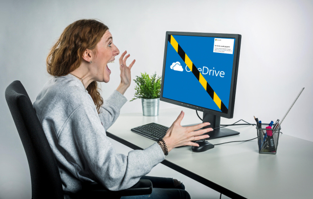 Erschrockene Frau vor gesperrtem PC mit OneDrive-Logo