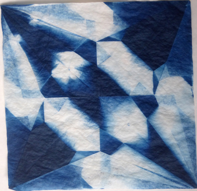 Square image in shades of blue and white, showing a geometric pattern equivalent to the shapes produced in a square of paper after being folded into an origami crane and then opened. The folds define triangles, diamonds and other shapes. Some areas are dark blue, some white, some tones of blue. In each one, the shapes are the same, but the blue and white is different.