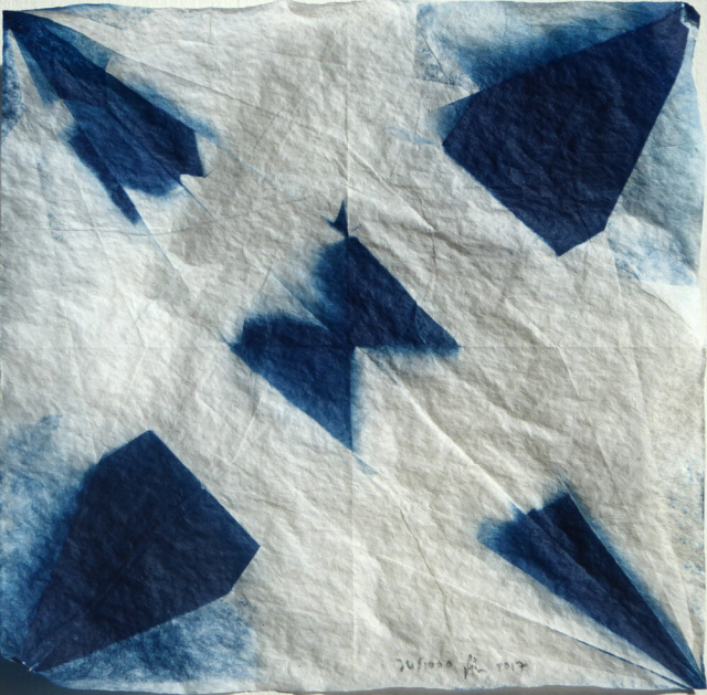 Square image in shades of blue and white, showing a geometric pattern equivalent to the shapes produced in a square of paper after being folded into an origami crane and then opened. The folds define triangles, diamonds and other shapes. Some areas are dark blue, some white, some tones of blue. In each one, the shapes are the same, but the blue and white is different.