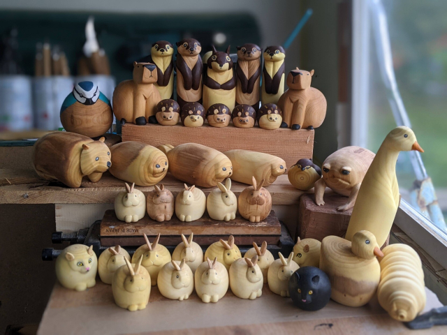 Ensemble de sculptures sur bois disposées en plusieurs rangées surélevées. Au premier rang, 5 lapins, 1 chats noir, 1 canard et 
 1 tardigrade. Deuxième rang, 1 chat, 5 lapins , de nouveau un chat, 1 canard coureur. Troisième rang : 5 lapins dodus, 1 grenouille des pluies du désert. Quatrième rang, 1 wombat, 3 phoques allongés, 1 troglodyte mignon. Cinquième rang, 1 mésange bleue, 1 capybara, 5 hérissons, 1 capybara. Sixième rang, 2 loutres, 1 écureuil, 1 loutres.