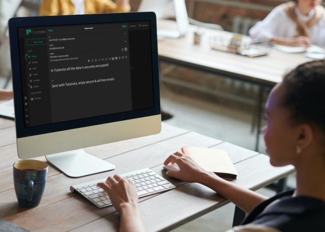 Woman at a PC using Tutanota in dark mode.