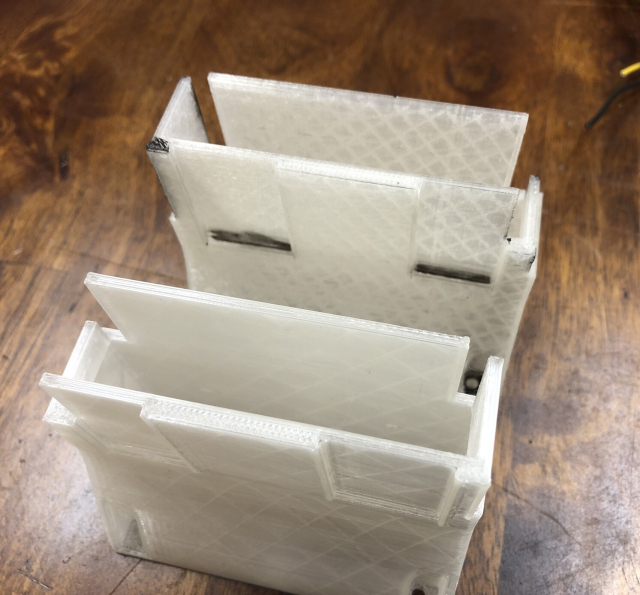 Two Xeon Phi fan shrouds next to each other on a table. Version 2 is in the back, marked up for fitment issues. Version 3 is next to it, completely mirrored because Case didn’t check the X and Y axis on the Ender 5.