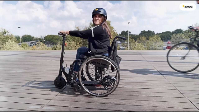 Women in a wheelchair attached to a scooter, wearing a safety helmet 