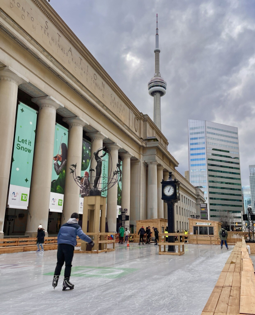 Temporary skating rink on a plaza in front of the train station with the CN Tower in the background