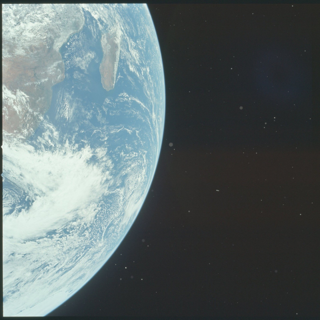 A color photo of Earth taken by the Apollo 17 astronauts. The arc of the planet cuts down the middle of the photo, with part of Earth occupying the left-hand side of the frame. There is a great deal of swirling white cloud cover over blue oceans and brown land masses. Madagascar is visible, as well as parts of Mozambique and Zimbabwe.