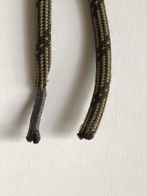 Extremos de unas agujetas; uno de ellos ya está envuelto con hilo para que no se deshilache.