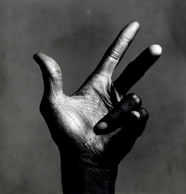 Black and White photo of Miles Davis' left hand against a murky gray background, ring & little finger folded in