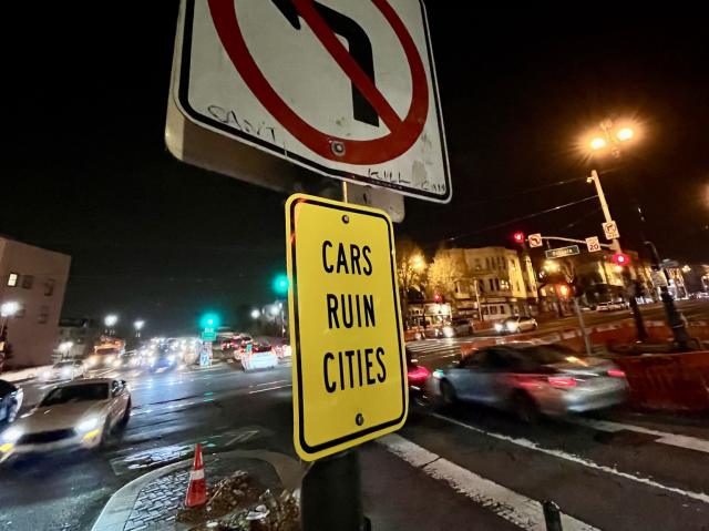 A street sign that says “cars ruin cities”