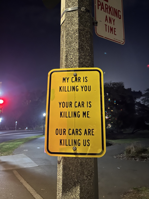 A street sign that says “my car is killing you / your car is killing my / our cars are killing us”
