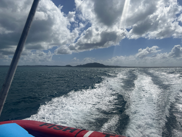 Wake of boat in sea with island in background