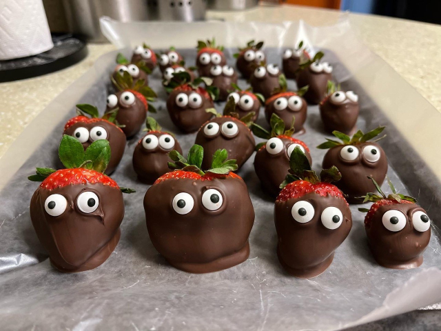 A tray of chocolate-dipped strawberries. Each strawberry has a pair of eyes.