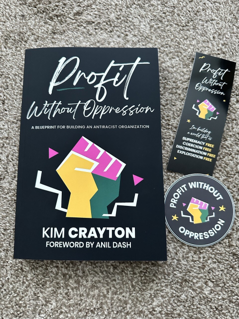 A copy of the book “Profit Without Oppression: A Blueprint for Building An Antiracist Organization” with a Profit Without Oppression bookmark and sticker 