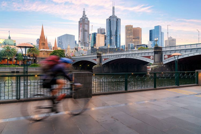 Person on bike riding on bike-lane next to river in city