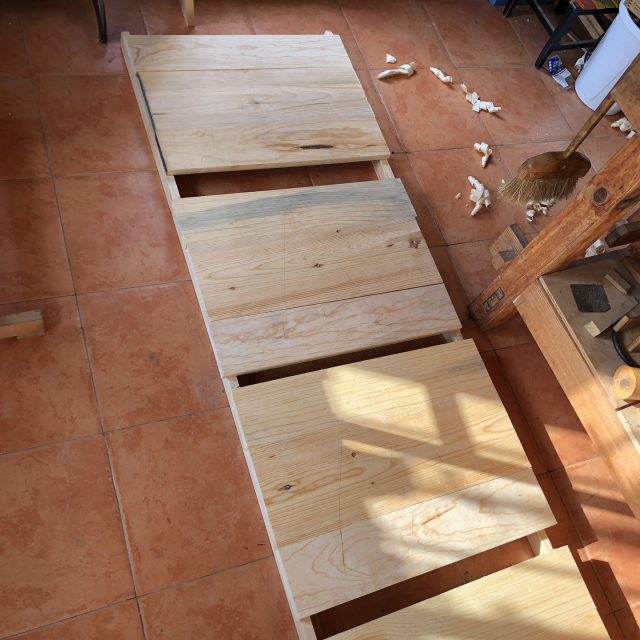 Cuatro de las tapas, puestas sobre dos tiras de madera en el suelo. Cada tira sostiene un extremo de cada tabla.