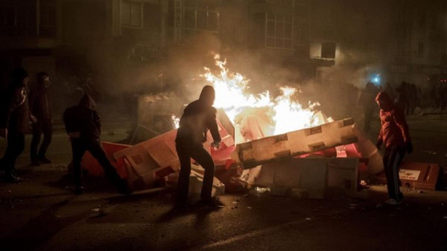 People maintaining a burning barricade.