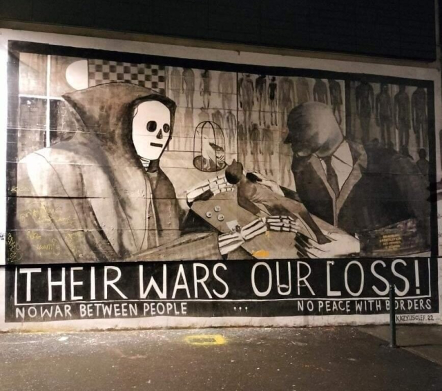 Large  mural featuring a grime reaper and a faceless business man at a table and the words "Their Wars, Our Loss! No wars between people, No peace with borders"