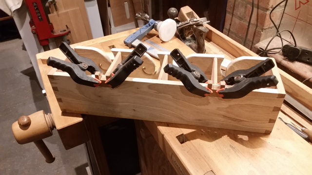 hinge parts are being held in place by several plastic clamps as wood glue dries.