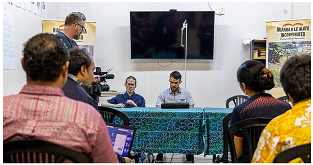 Photo of Mick and Jamie speaking to a room of people from the Samoa Blind Persons Association