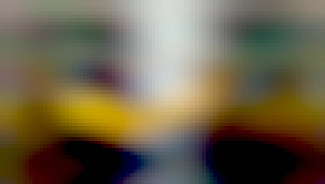 A photograph of a banana lying against a white vase on top of a black table. The table is reflecting a small amount of light toward the center.