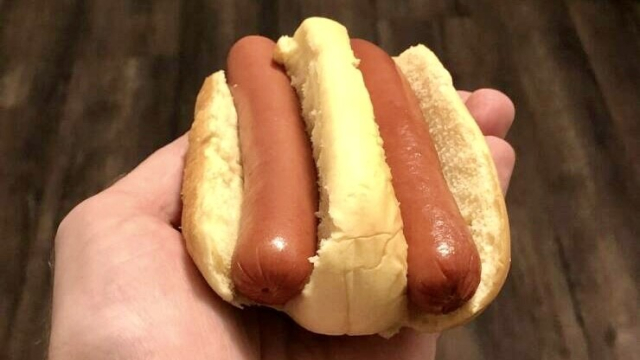 Oversized hot dog bun sliced twice and containing two hot dogs.