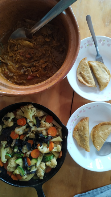 Los platillos en sus recipientes (vista superior). Arriba a la izquierda la cazuela de barro con el curry de cabeza, abajo a la izquierda el sartén de hierro fundido con las verduras. A la derecha dos platos con dos quesadillas cada uno.