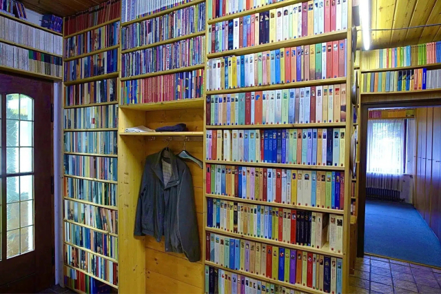 Photo of the entryway of a house with the walls all but covered in books in bookcases. 