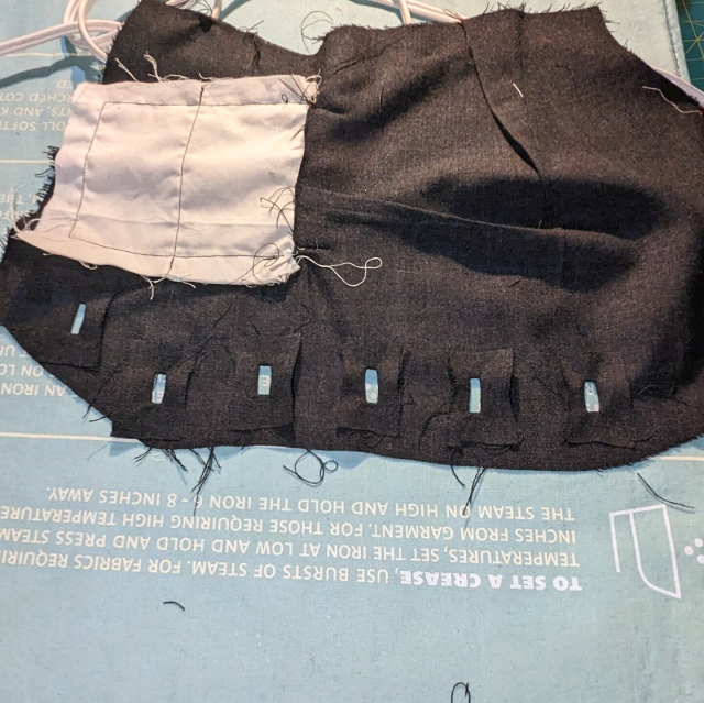 Button hole linings pressed flat on the inside of the front piece of a waistcoat, framing the rectangular button holes