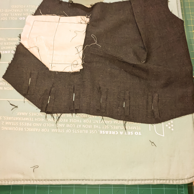 The wrong side of the front left piece of a waistcoat in progress, with button hole linings folded over the gaps