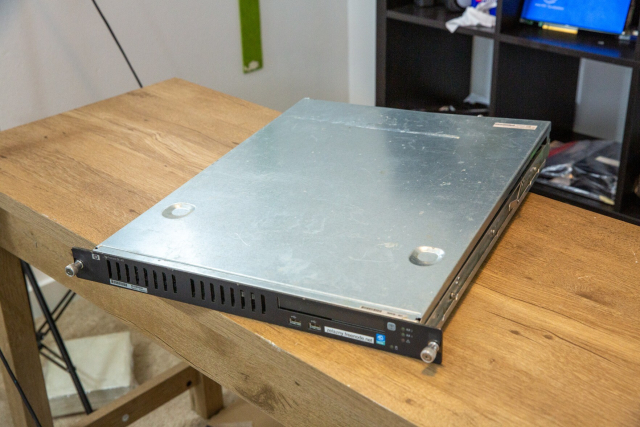 The entire server sitting on a table. It has a black matte front panel with vertical grills.
