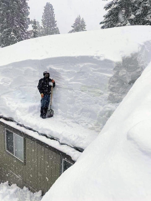 Man shoveling snow off of his roof. 