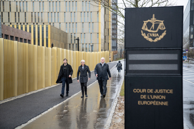Drei Personen laufen auf die Kamera zu. Rechts im Bild ist ein Schild was den Europäischen Gerichtshof ausweist. Bild: Nicolas Leblanc, CC-BY 4.0