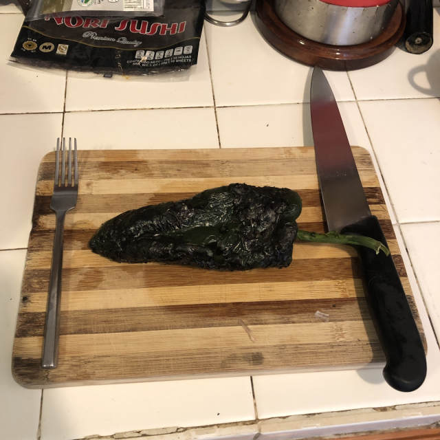 Chile, tenedor y cuchillo sobre una tabla de picar.