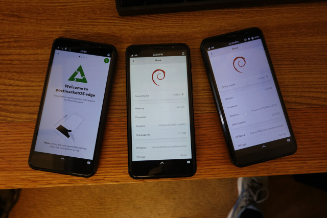 Three Librem 5s on a desk. One is running pmOS, two are running Mobian