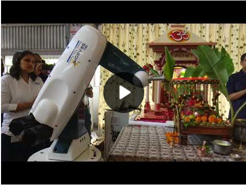 Screenshot of a Youtube video showing a robotic arm performing "arti", a Hindu ritual in which light -- here, candles -- is offered to a deity (in this case, Ganesha)