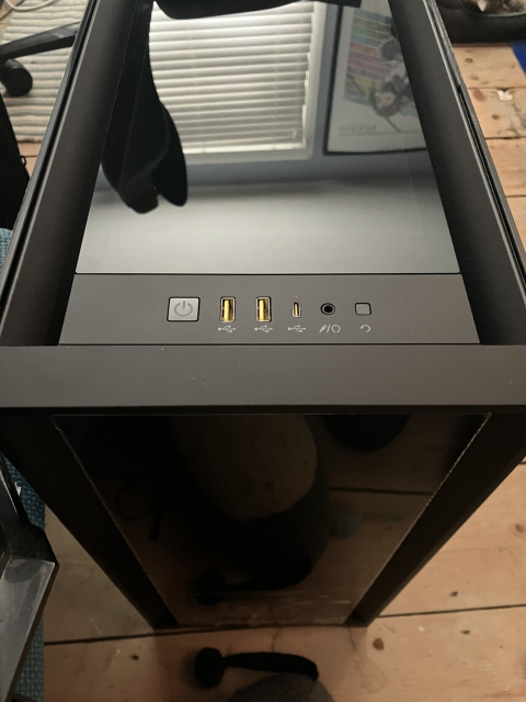 The top view of a desktop computer, showing the power button and various input ports, with a glassy panel covering the top of the case