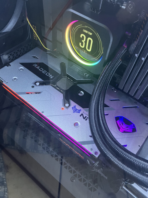 A detail of the inside of a desktop PC, with the focus on the Radeon graphics card, and the CPU cooler display showing the coolant temperature at 30 degrees Celsius
