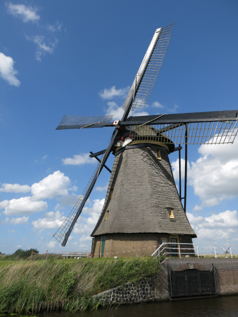 Gray faceted windmill sitting by a waterway