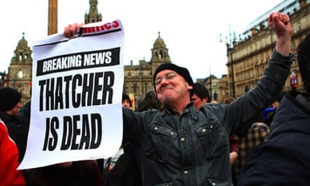 Celebrant with a triumphantly raised fist brandishing a newsprint poster in his other hand reading "Breaking news: Thatcher is dead" 