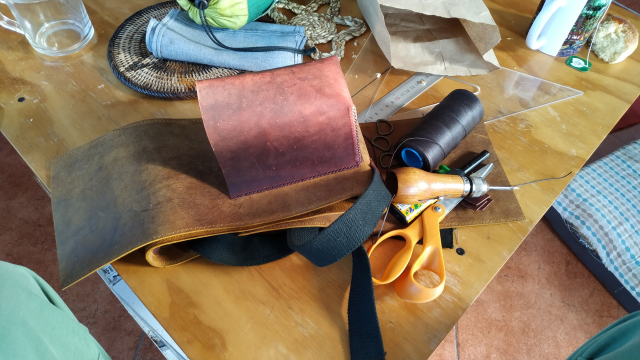 una pieza de piel amarilla amontonada con algunas herramientas sobre una mesa de madera.