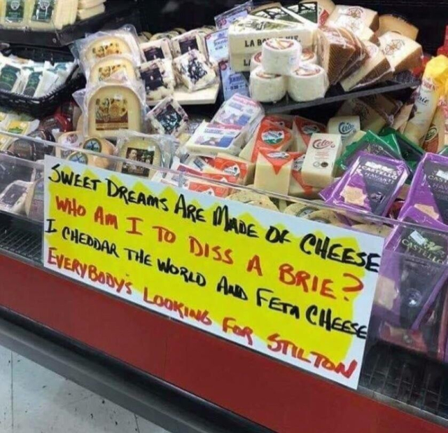 A pile of cheese in a supermarket, the sign below the cheese is a pun-filled ode to the Eurythmics single 'Sweet dreams (are made of this)' says 
'Sweet dreams are made of cheese. Who am i to diss a brie. I cheddar the world and feta cheese. Everybodys looking for stilton'